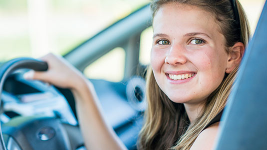 Teenage girl holding the steering wheel with her right hand