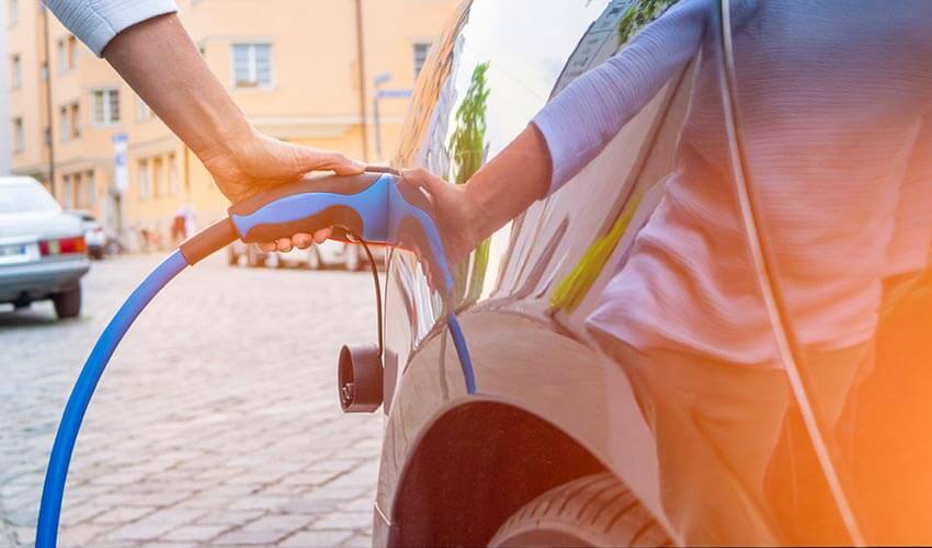 A hand holding a charger into an electric vehicle.
