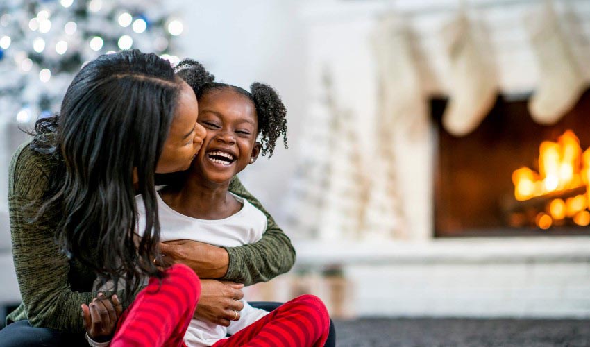 https://www.caasco.com/-/media/caasco/blog/insurance/2020/11/eight-ways-to-deck-your-halls-safely/blog-img--mother-and-daughter-cuddling-in-front-of-a-holiday-fireplace.jpg