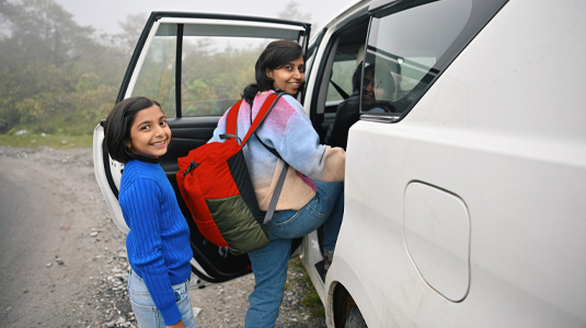 Two kids getting into the back of their car